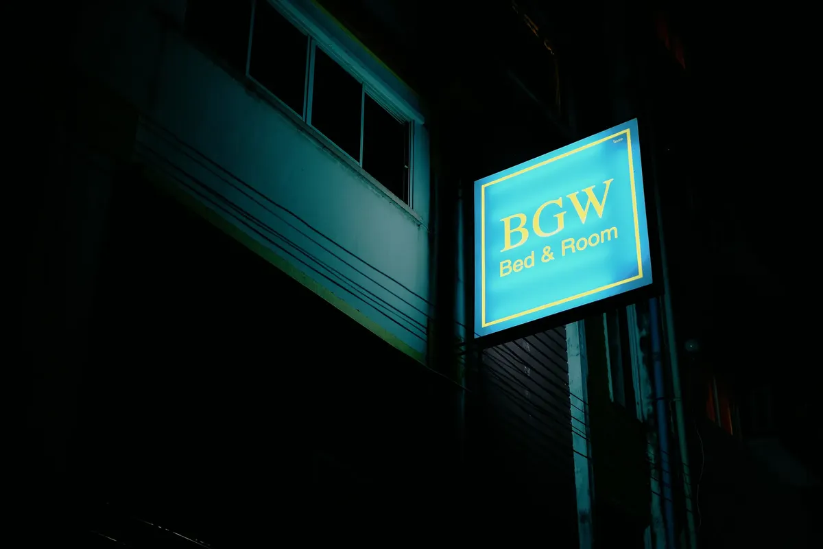 Low angle night shot of BGW Bed & Room sign on building wall in Phuket, Thailand.
