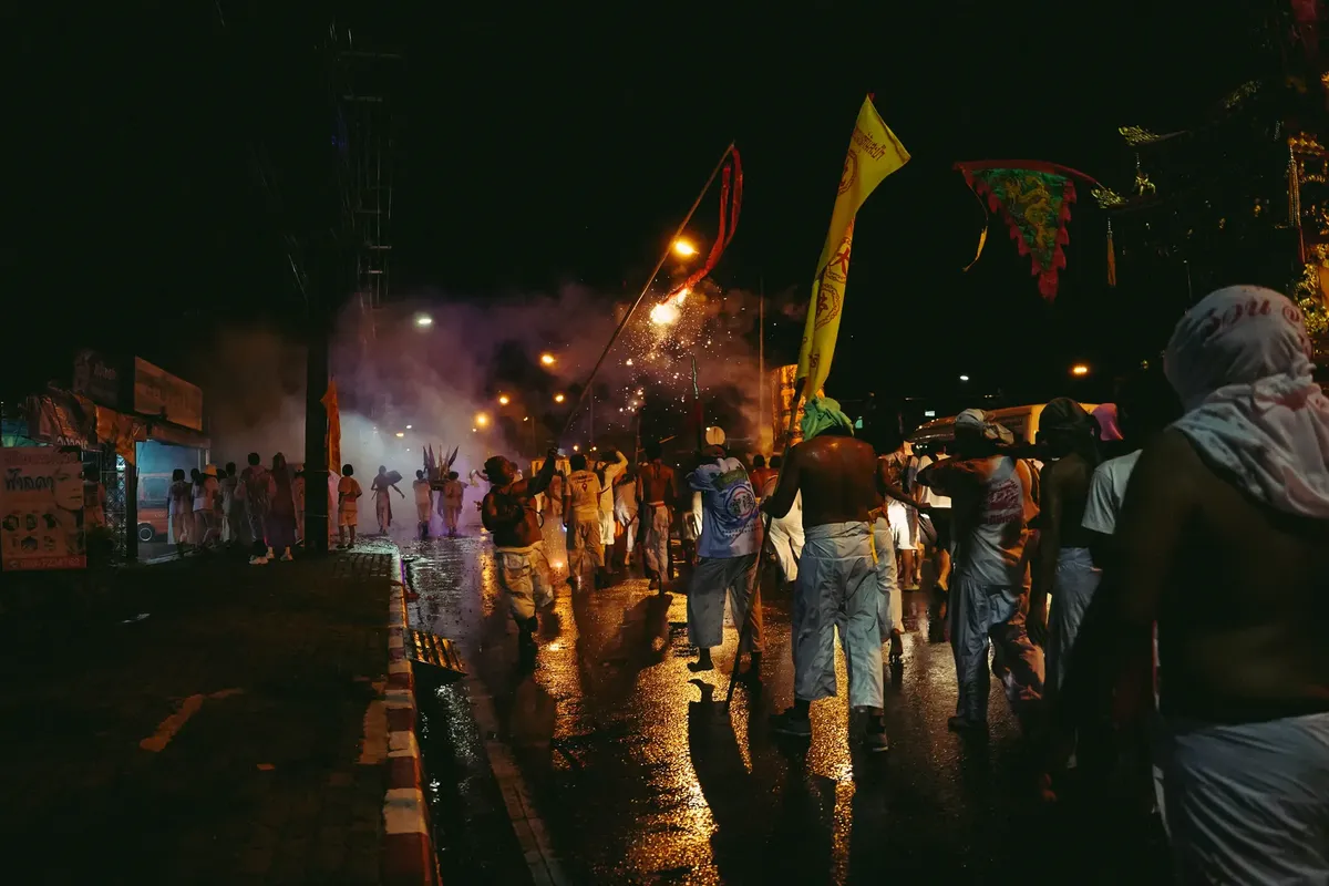 Colorful night parade with people in traditional attire celebrating on Phuket street.
