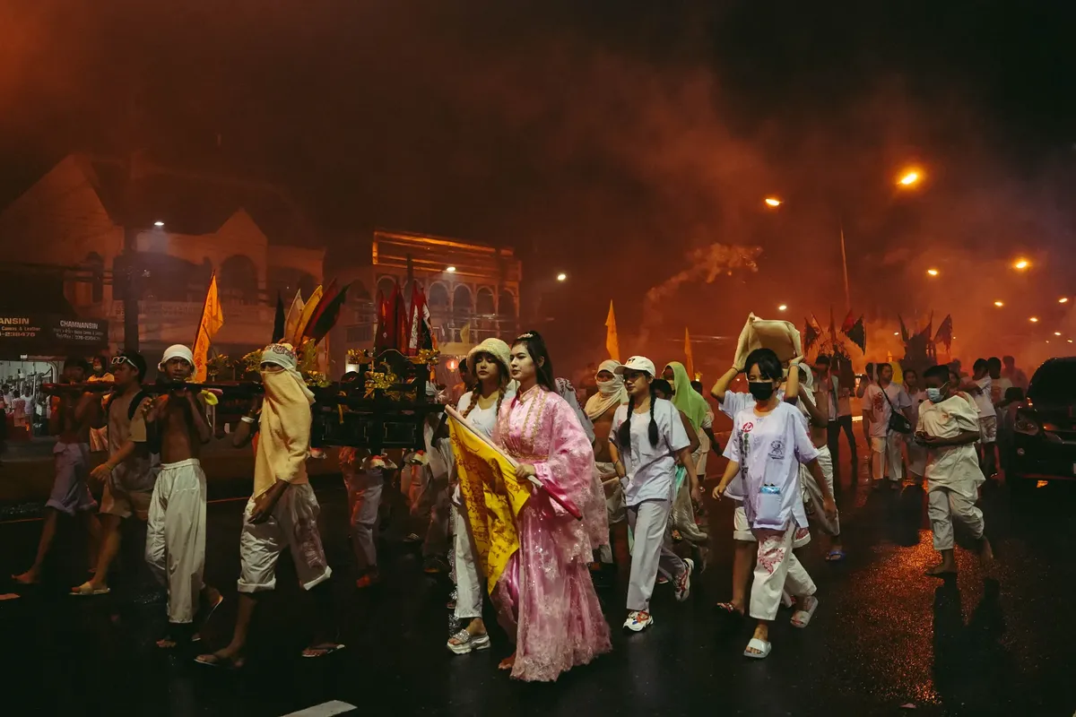 Captivating night parade with traditional attire during a cultural festival in Phuket, Thailand.