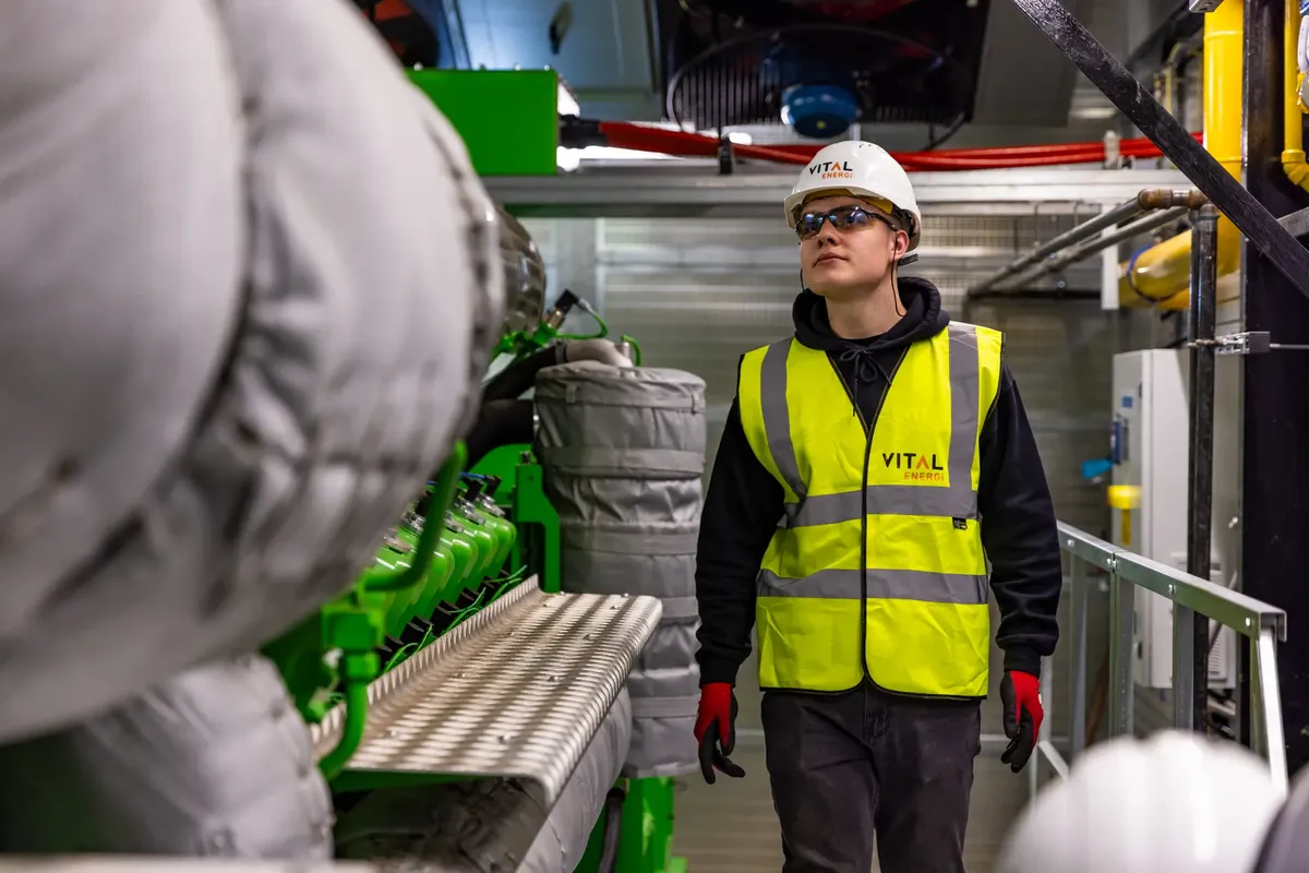 Man in safety gear inspecting factory equipment, ensuring quality control and safety standards.