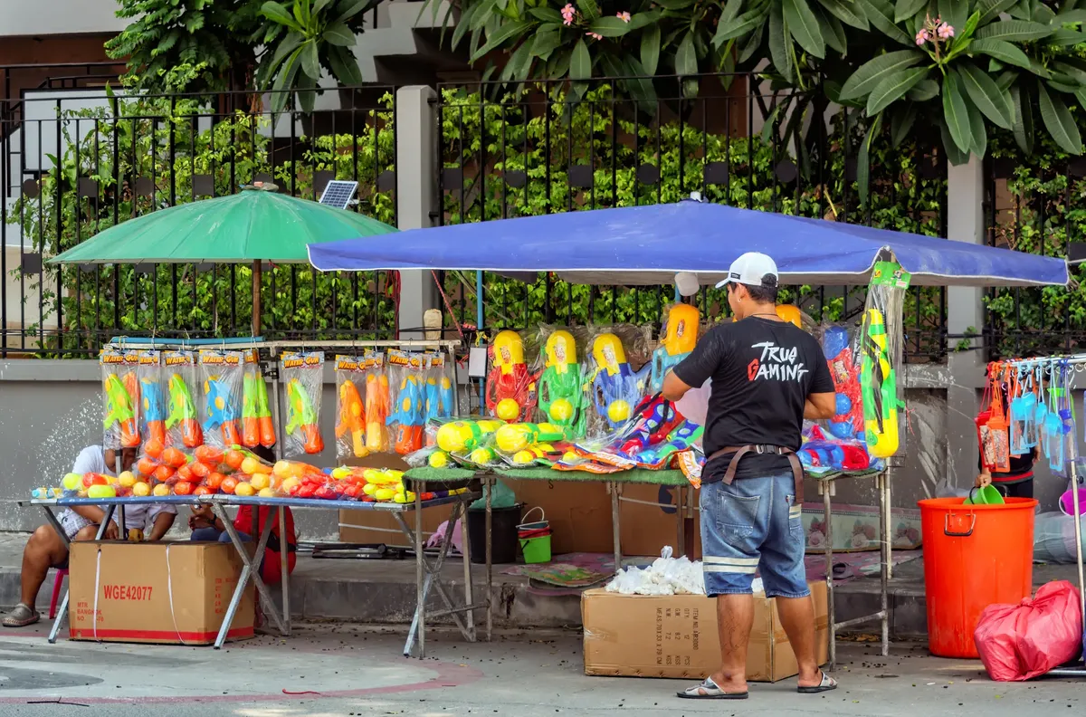 A vibrant street stall selling colorful water guns in Pattaya for the Songkran festival.